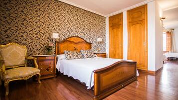 A bedroom with a wooden bed, a nightstand, a lamp, a chair, and a dresser.