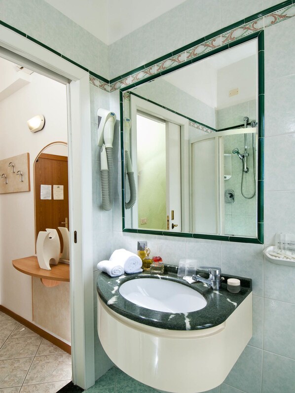 Un baño moderno con un lavabo curvo, un espejo grande y una zona de ducha.