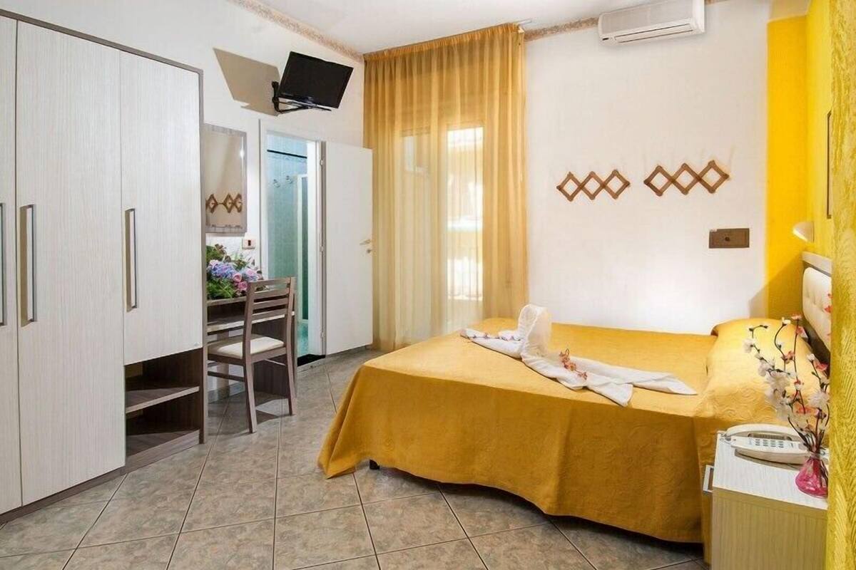 A hotel room with a bed, a desk, and a chair.