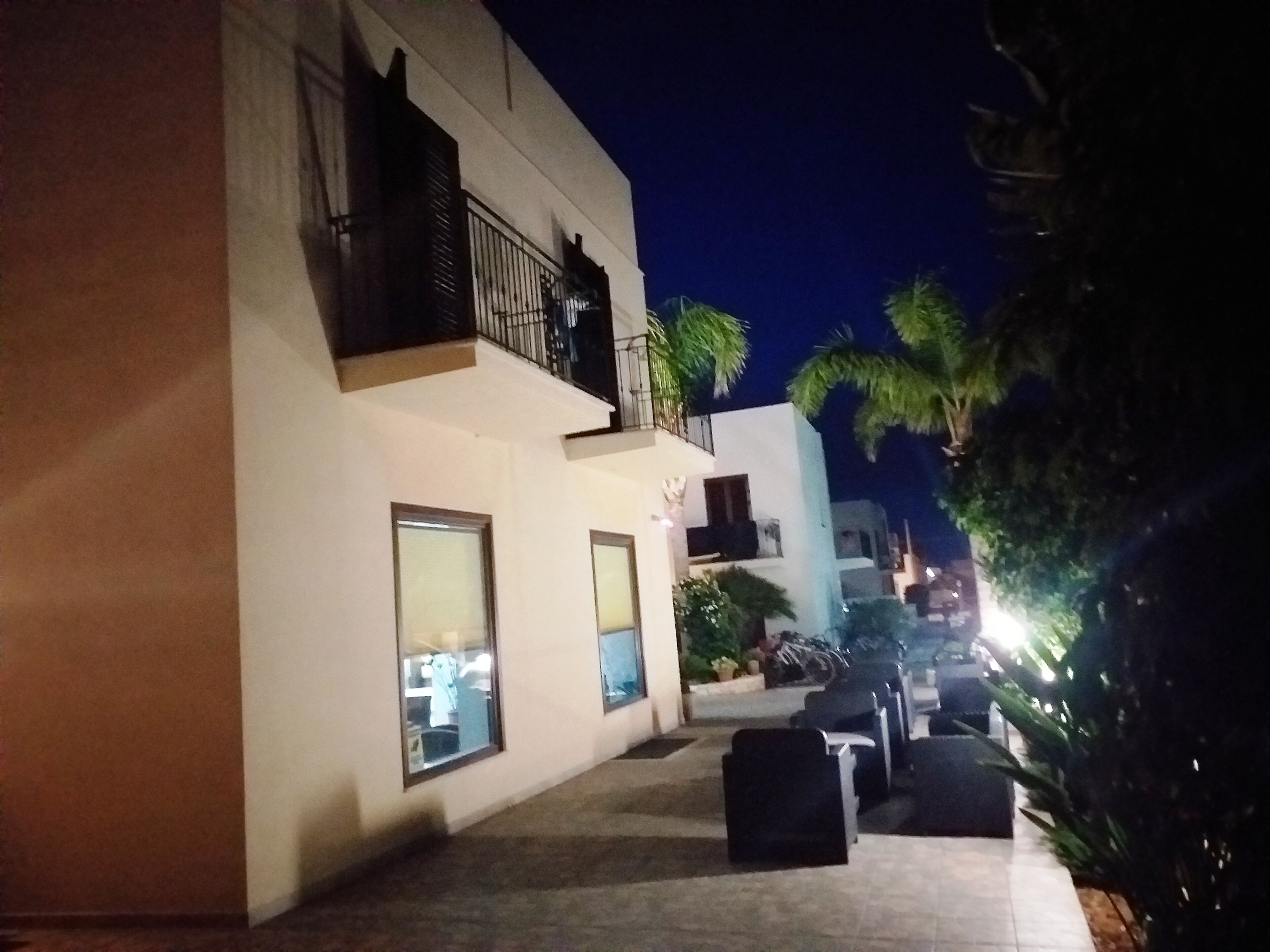 Vista nocturna de un edificio con balcón y zona de estar al aire libre.