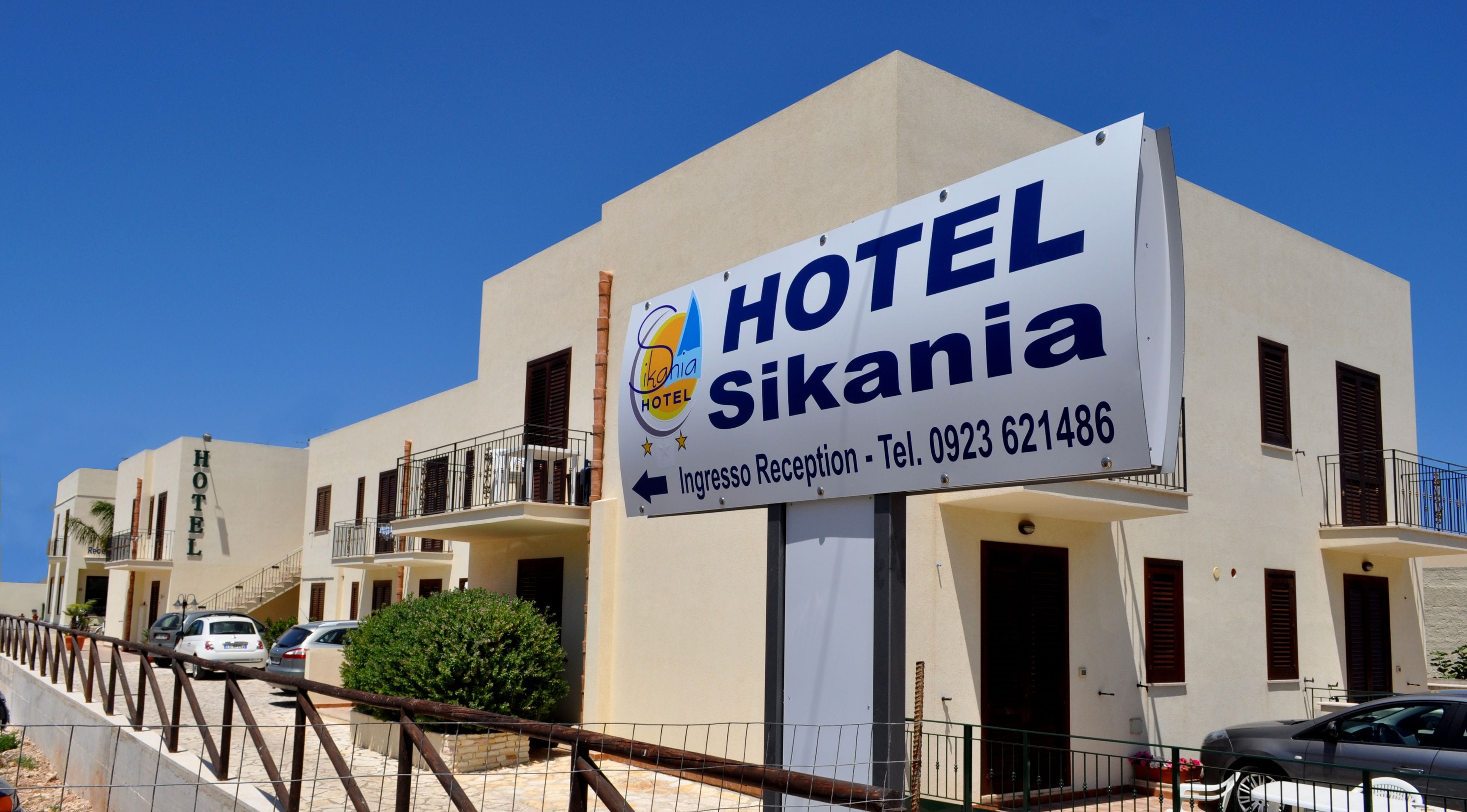 A hotel sign with the name "HOTEL Sikana" and a reception direction.