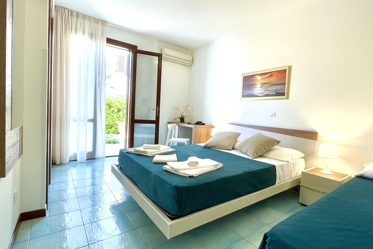 Une chambre d’hôtel avec un lit, un bureau, une chaise et une vue sur l’extérieur.