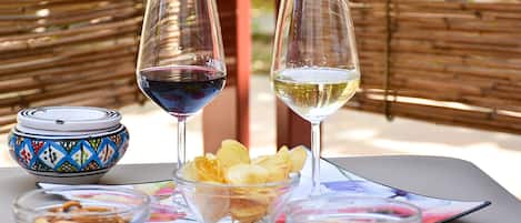 A table with two wine glasses, a bowl of chips, and two small bowls of nuts.