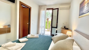 Een hotelkamer met een bed, een stoel, een bureau, een lamp en uitzicht op het groen.