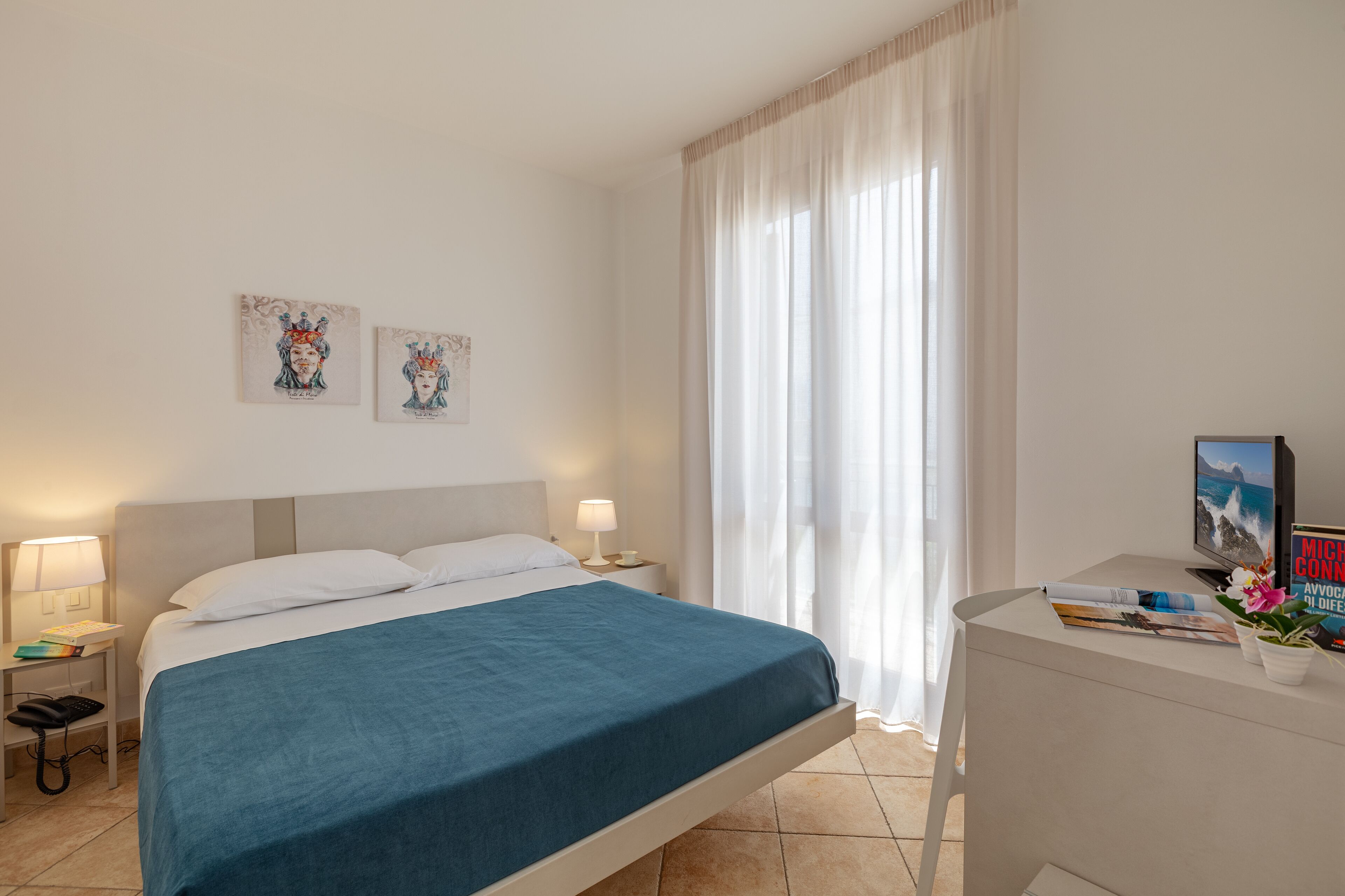 A hotel room with a bed, bedside tables, a desk, and a TV.