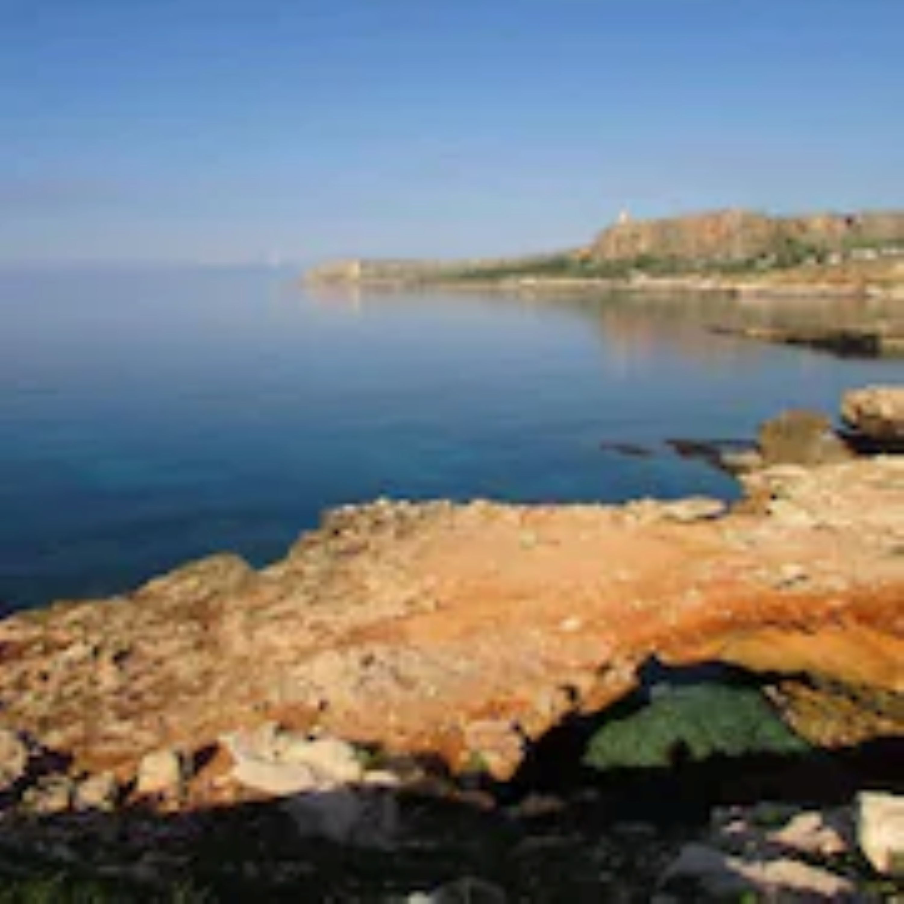 Un paisaje costero con terreno rocoso y una vista despejada del mar.