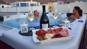 Een bubbelbad met twee personen, een fles Prosecco, wijnglazen en een bord eten.