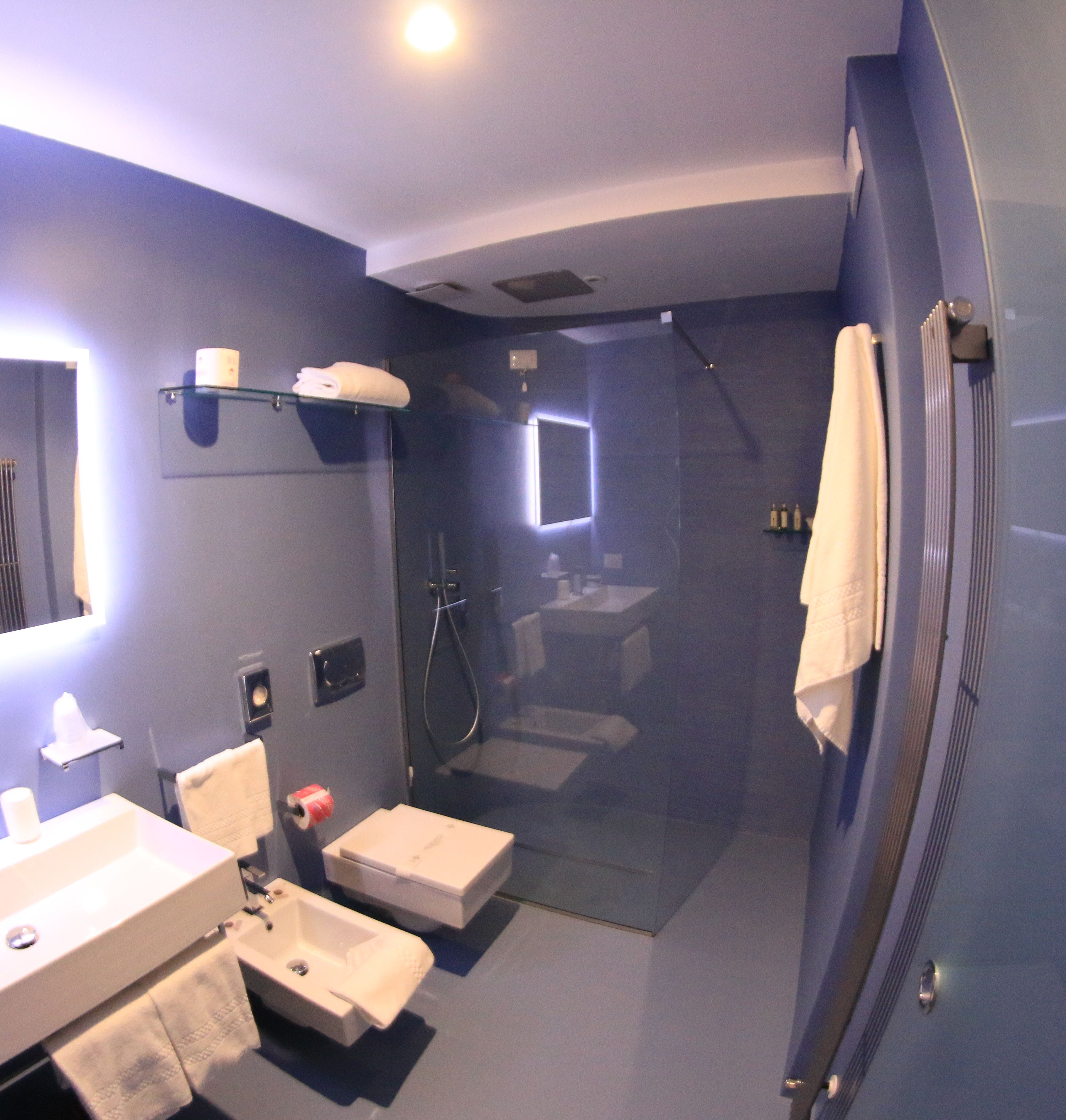 A modern bathroom with a glass-enclosed shower, a sink, and a mirror.
