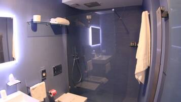 A modern bathroom with a glass-enclosed shower, a sink, and a mirror.