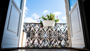 An open door with a potted plant on a balcony railing. - Albergo del Sedile (Matera)