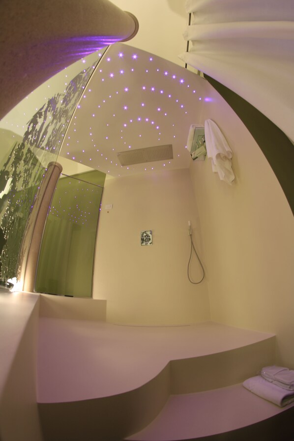 Een badkamer met een gebogen bankje, een douche en een plafond met kleine lampjes.