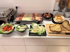 Un bufé con una variedad de alimentos, incluyendo carnes, quesos y pan.