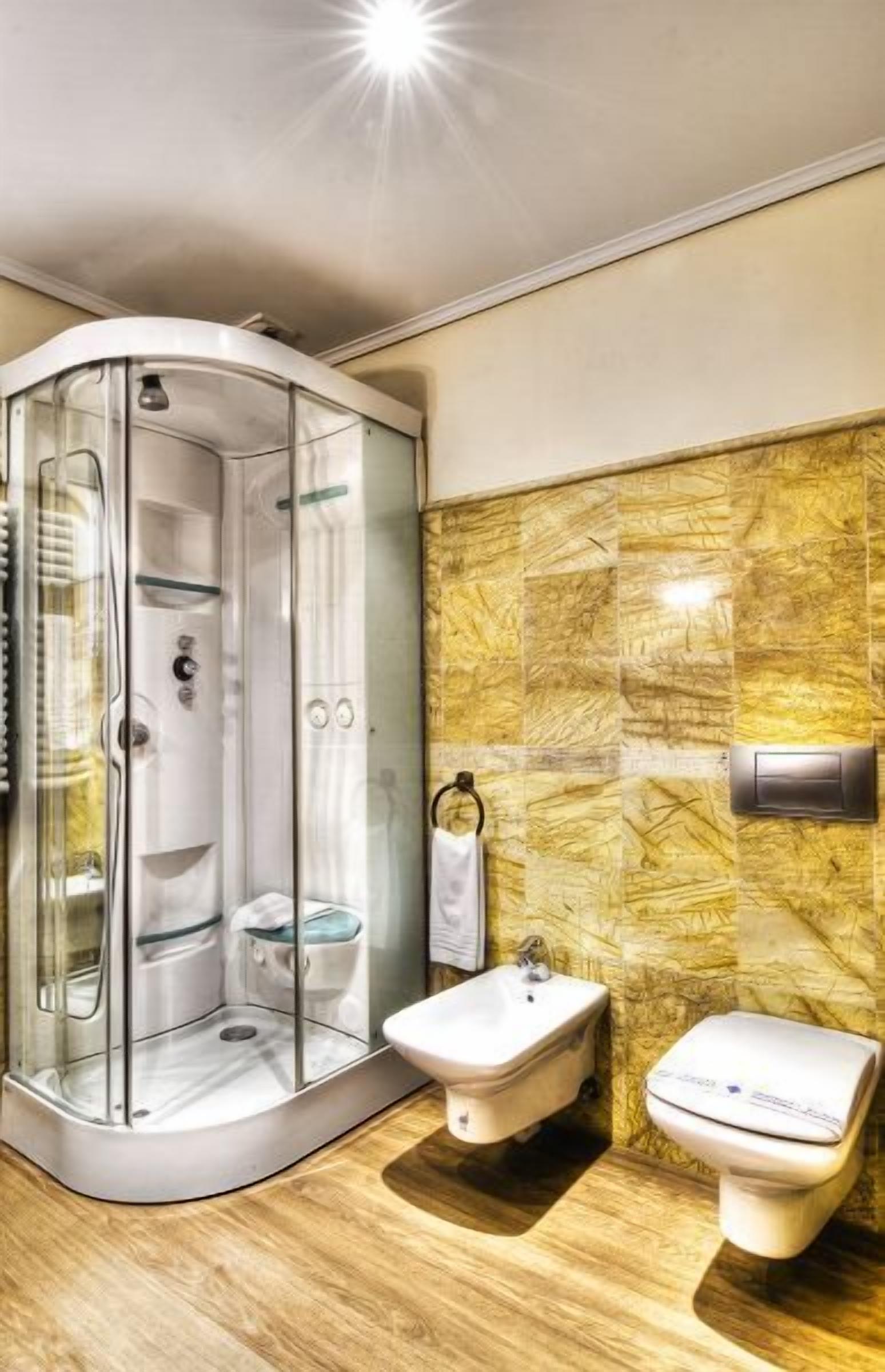 A modern bathroom with a glass-enclosed shower, a bidet, and a toilet.