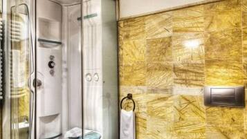 A modern bathroom with a glass-enclosed shower, a bidet, and a toilet.