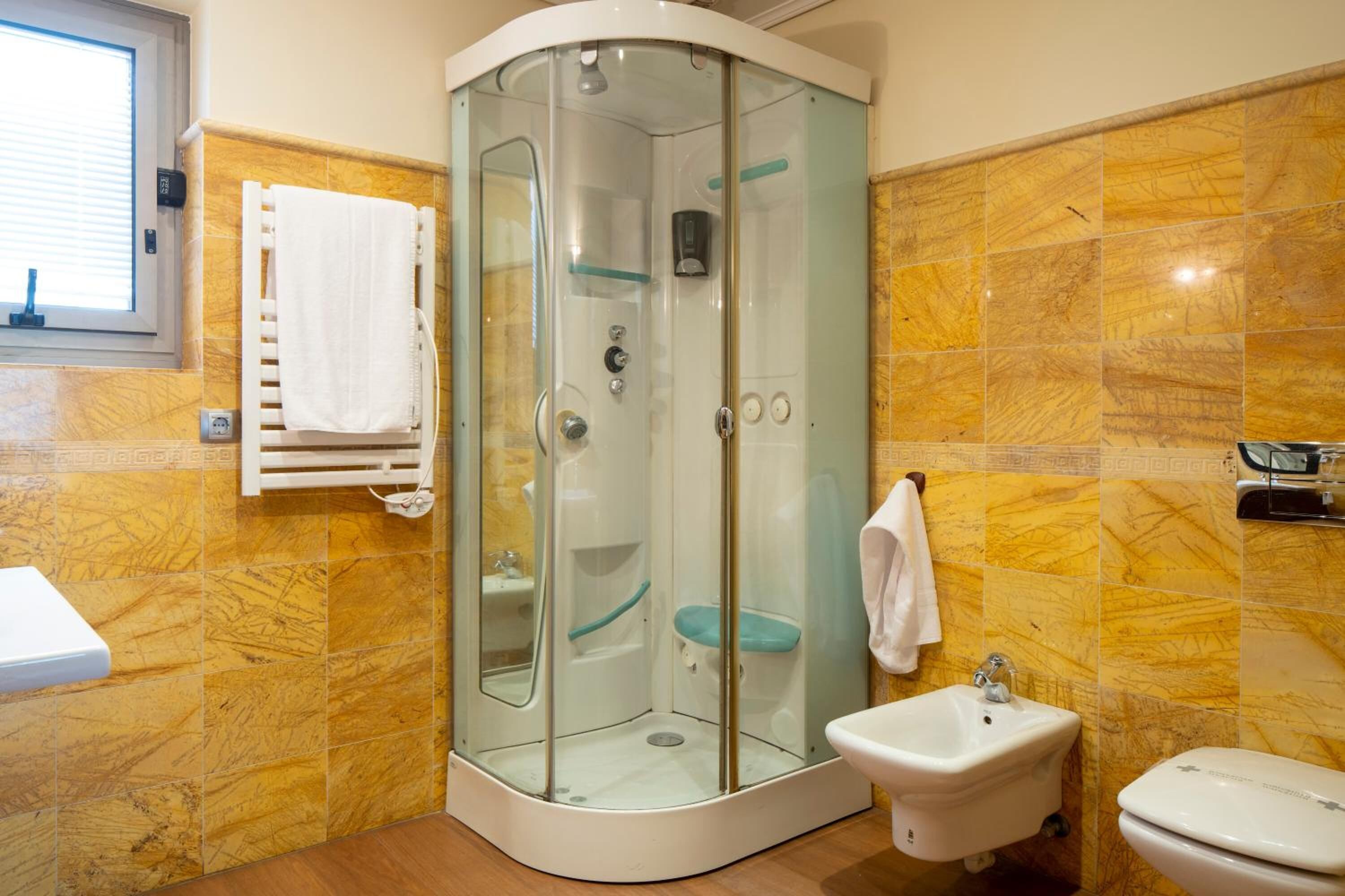 A bathroom with a glass-enclosed shower, a sink, and a toilet.