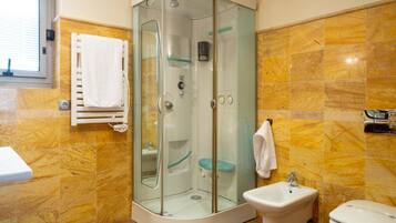 A bathroom with a glass-enclosed shower, a sink, and a toilet.