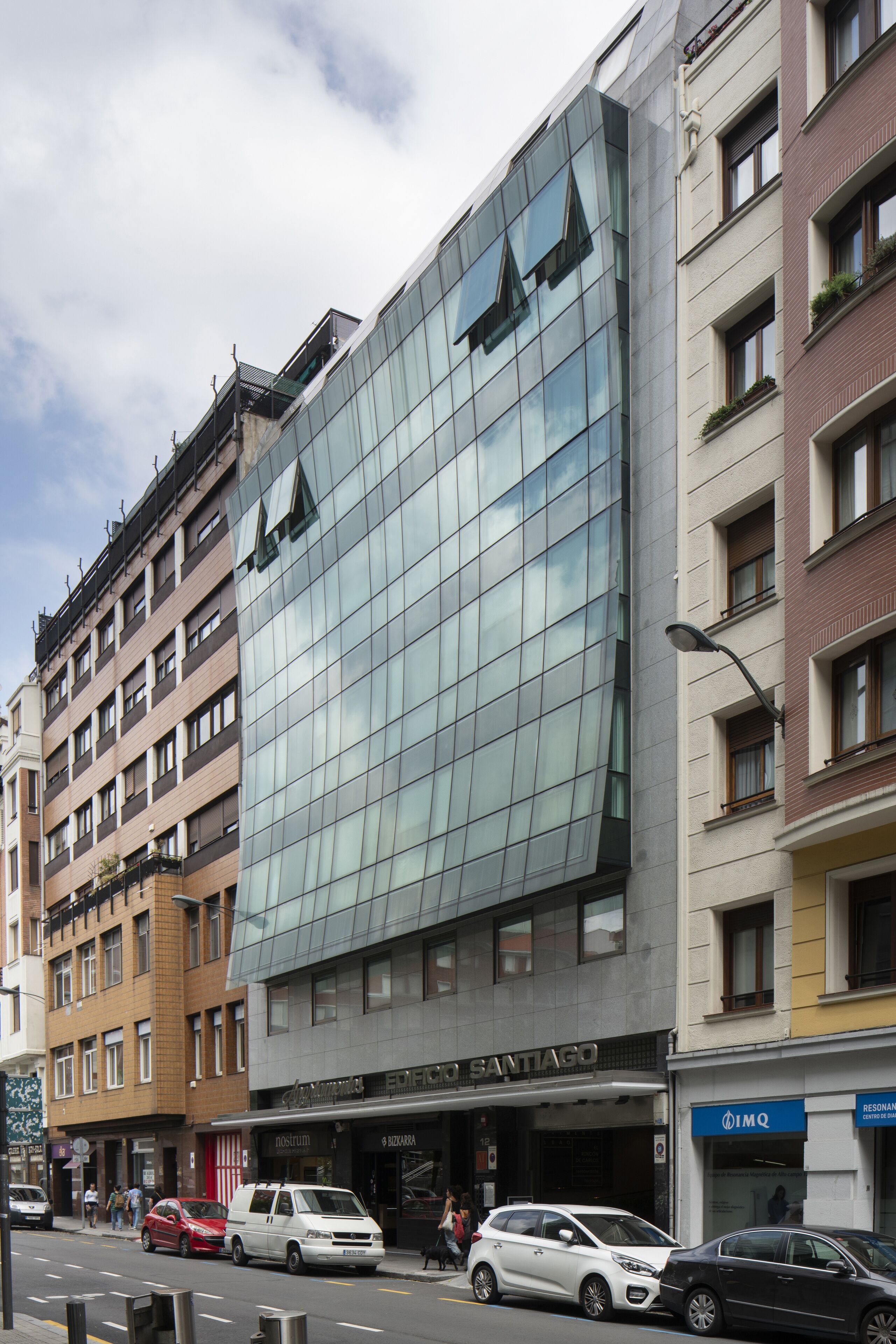 Un edificio moderno con fachada de vidrio y un cartel que dice 'Santiago'.