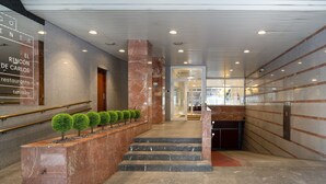 Un intérieur moderne avec des escaliers en marbre, un comptoir d’accueil et une enseigne indiquant « El Rincón de Carlos Restaurante ».