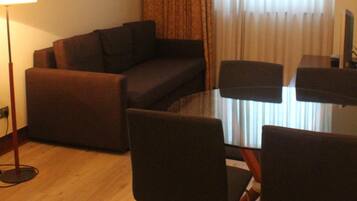 Una sala de estar moderna con un sofá, una mesa de comedor con superficie de vidrio y sillas.