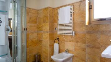 Un baño con cabina de ducha de vidrio, un lavamanos blanco y un perchero para toallas.