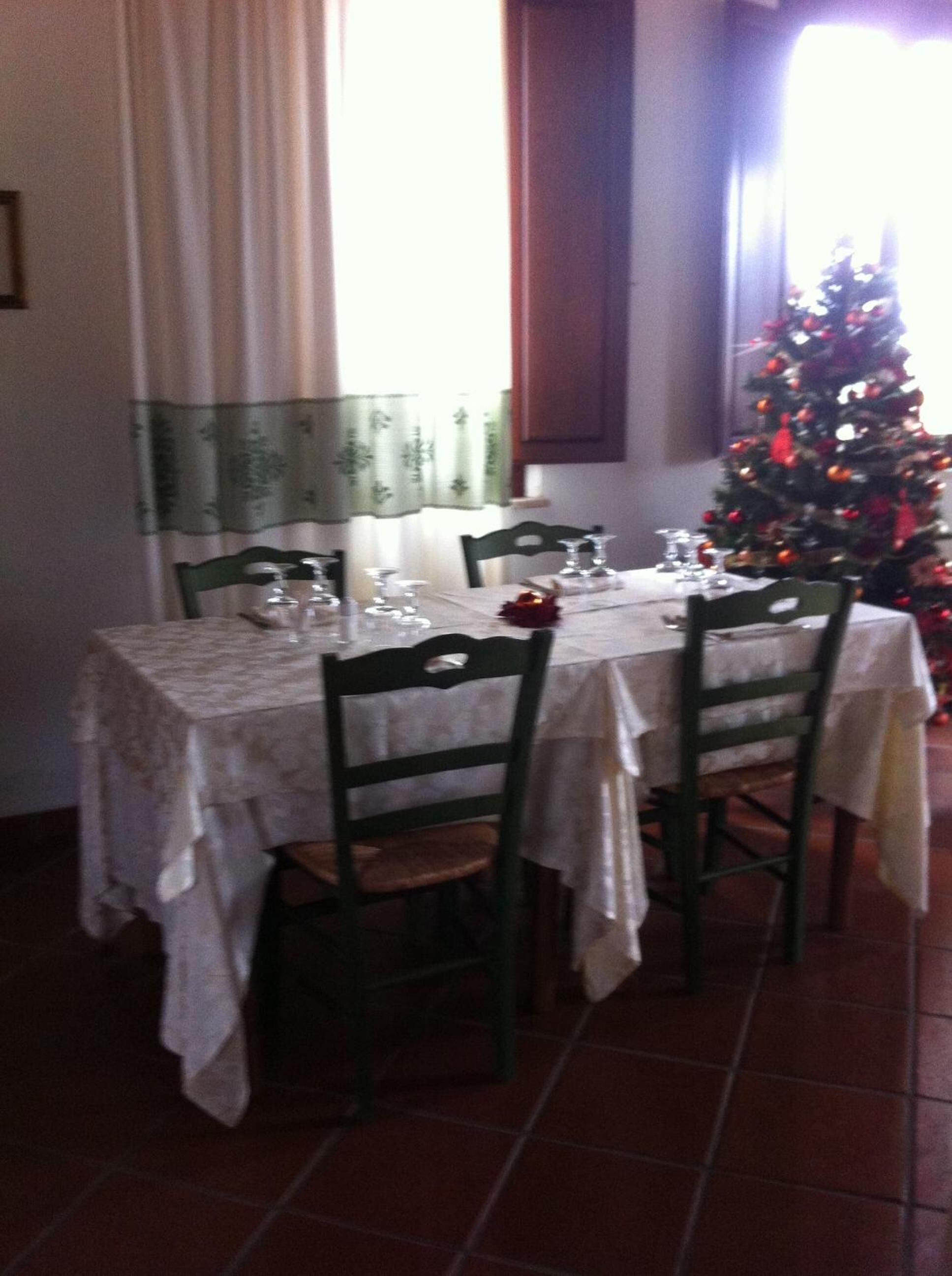 A dining area with a table set for four, chairs, and a Christmas tree in the background.