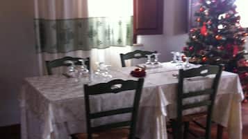 A dining area with a table set for four, chairs, and a Christmas tree in the background.