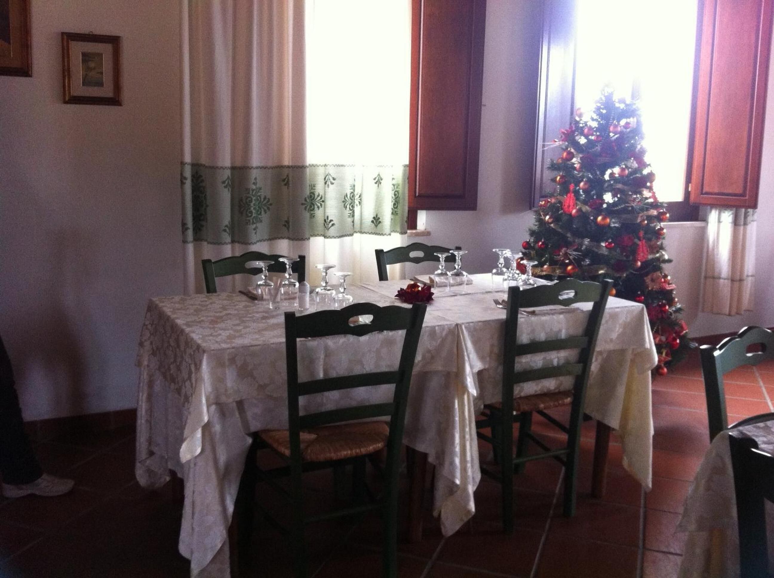 Un coin repas avec une table dressée pour quatre personnes, des chaises et un sapin de Noël.
