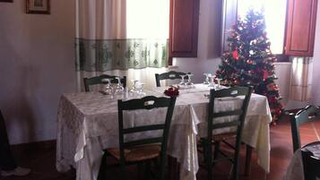 Un coin repas avec une table dressée pour quatre personnes, des chaises et un sapin de Noël.