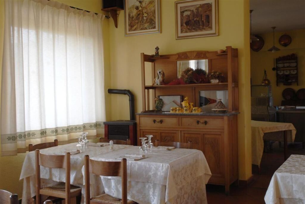 Un comedor con una mesa dispuesta para cuatro personas, armarios de madera y un radiador.