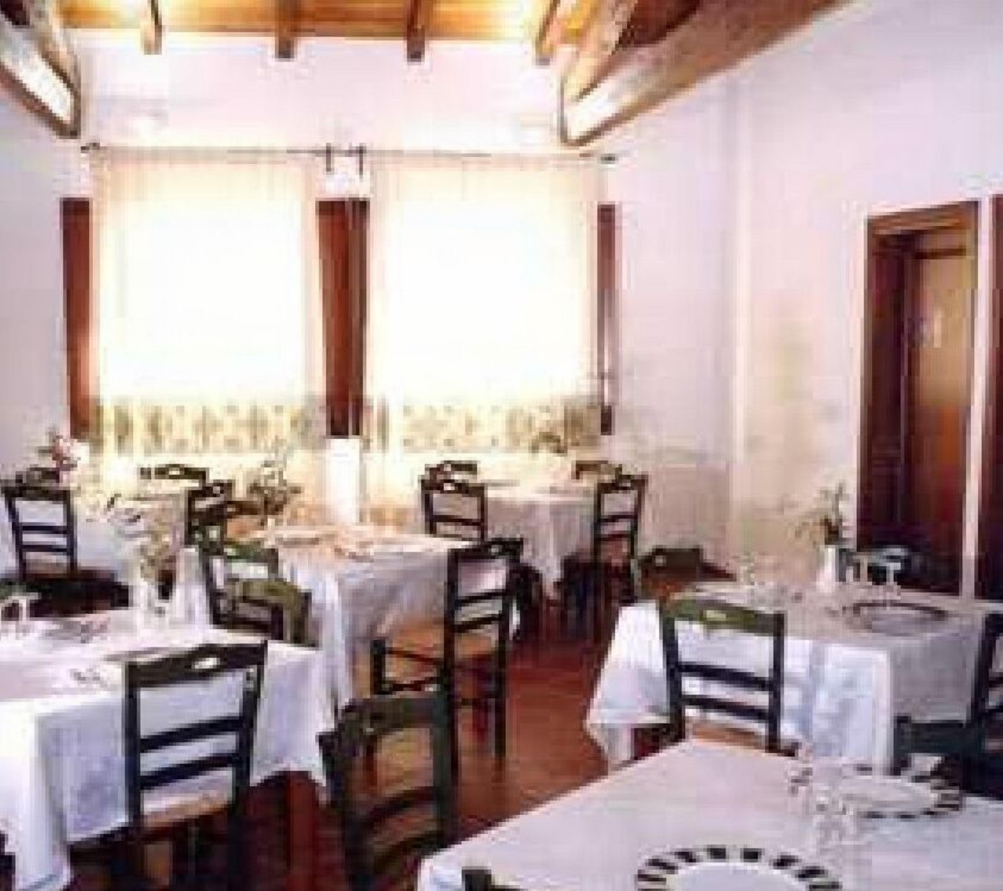 A dining area with tables set for multiple guests, featuring a classic interior design with wooden beams and white tablecloths.