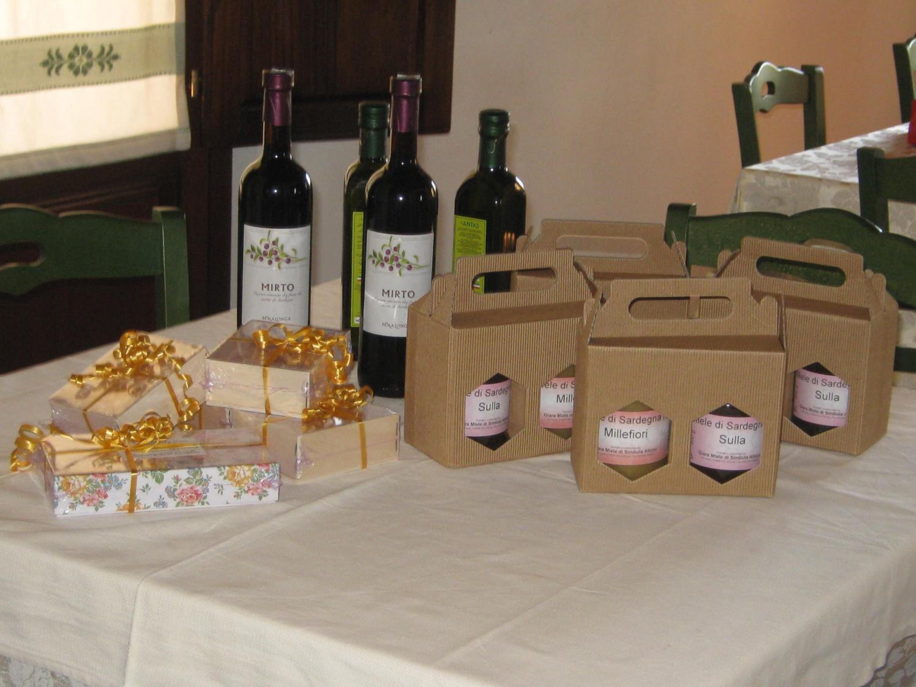 Una mesa con botellas de vino, cajas de regalo y bolsas de papel etiquetadas.