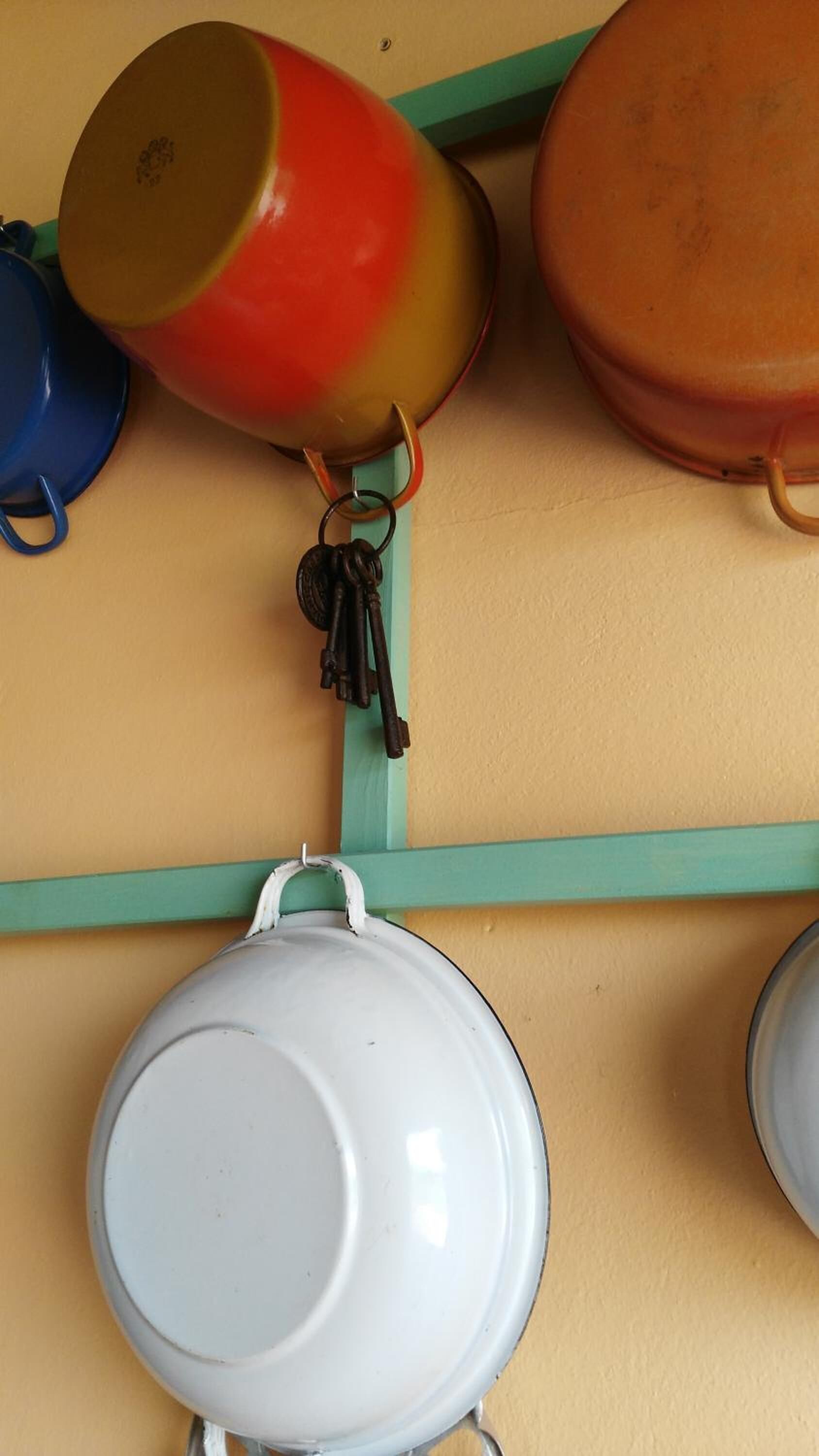 A kitchen with hanging pots and pans on a teal shelf.