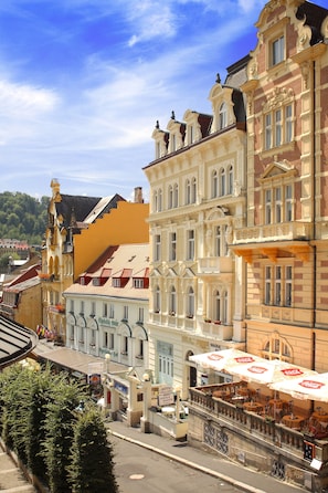 A row of historic buildings with ornate facades and a street cafe with outdoor seating. - Hotel Heluan (Karlovy Vary)