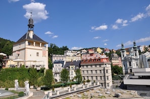 A historic building with a prominent tower and a restaurant named "KARL IV GALLERY THERAPY GRILL" on the ground floor. - Hotel Heluan (Karlovy Vary)