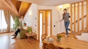 Una sala de estar acogedora con techo de madera, una mesa de comedor con sillas, un sofá y una escalera.