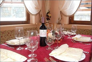 A table set for a meal with wine glasses, a bottle of wine, and a floral centerpiece.
