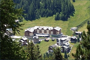 A large hotel with multiple buildings, surrounded by a forested hillside.