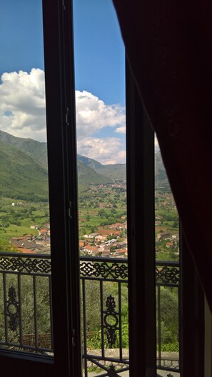 A balcony with a view of a valley, mountains, and a village.