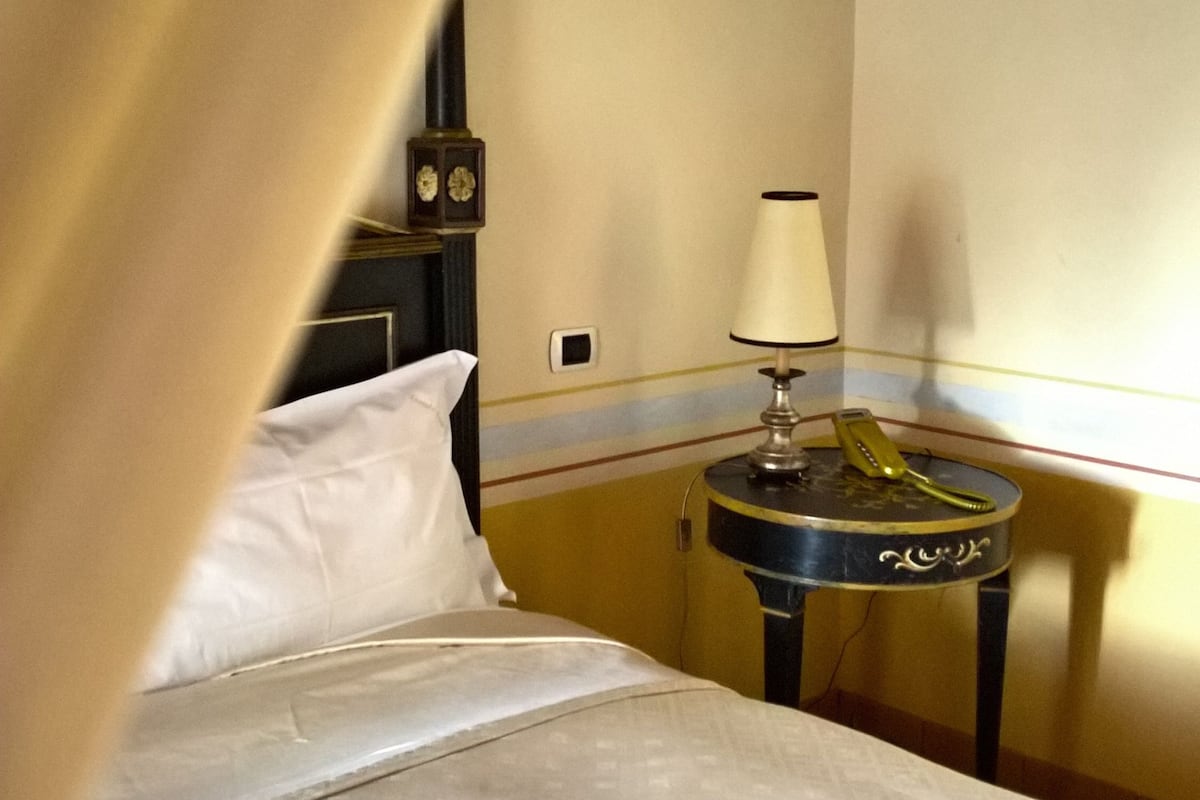 Une chambre d’hôtel avec un lit, une table de chevet avec une lampe et une horloge murale.