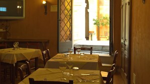 A restaurant with a long table set for dining, a chandelier, and a television on the wall. - Antichi Feudi Dimora d'Epoca (Teggiano)