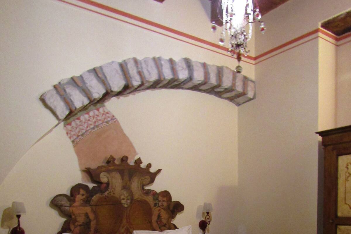 Un lit bien fait, avec une tête de lit en bois, deux tables de chevet avec des lampes et une arche décorative au-dessus du lit.