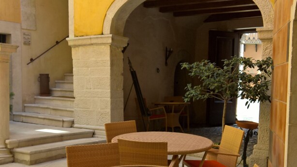 An outdoor patio with wicker furniture and red cushions, a stone staircase, and a yellow wall. - Antichi Feudi Dimora d'Epoca (Teggiano)