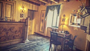 A room with a wooden floor, a desk with chairs, a lamp, and framed pictures on the wall. - Antichi Feudi Dimora d'Epoca (Teggiano)