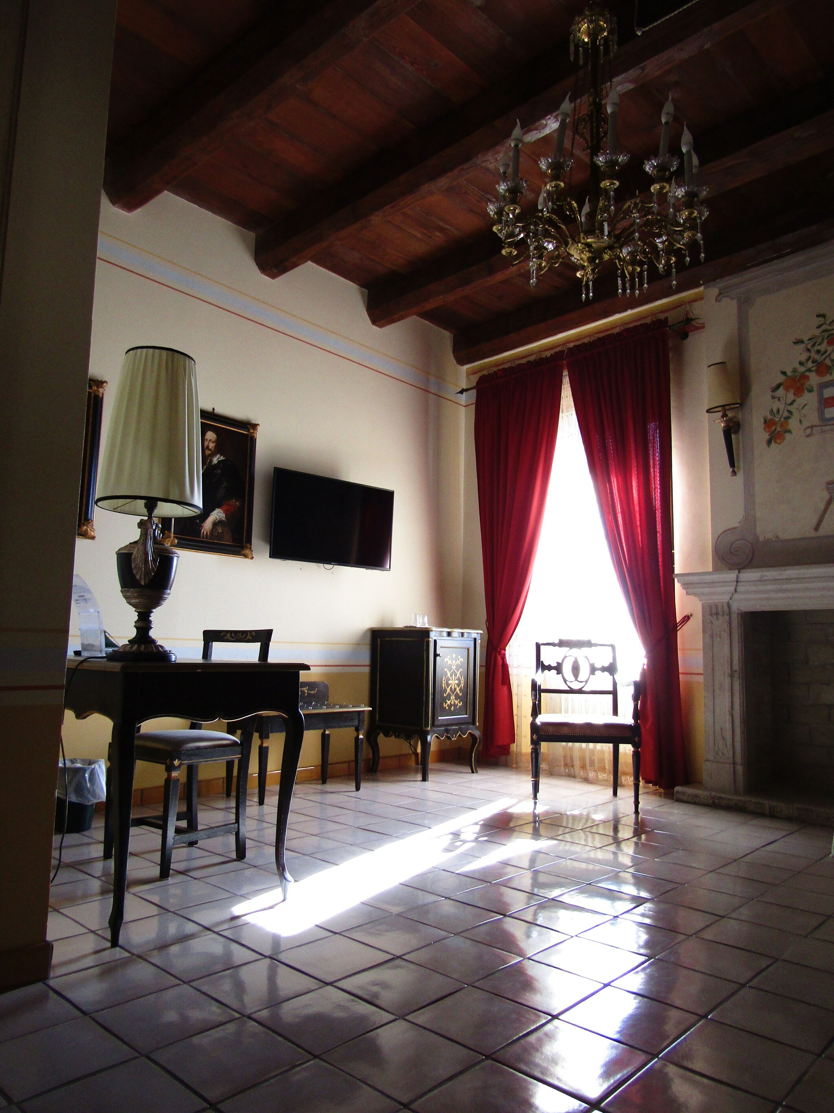 Una stanza con un lampadario, un camino, una televisione e un'area pranzo con sedie e un tavolo.