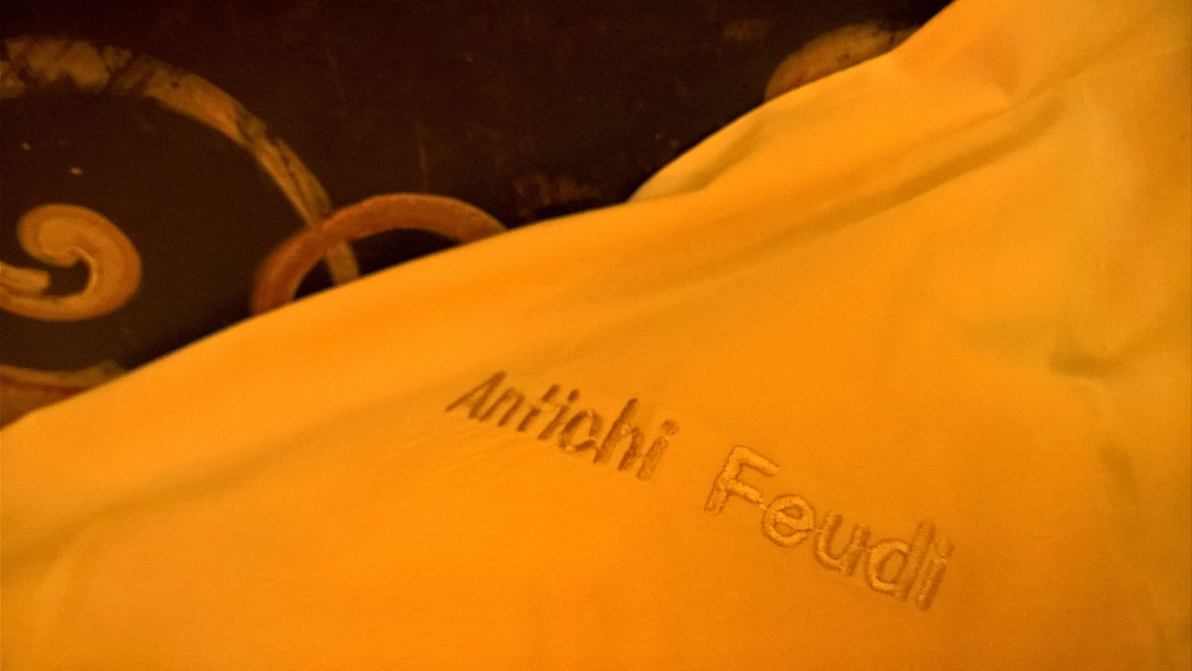 A close-up of a yellow fabric with the text "Antichi Feudi" embroidered on it.