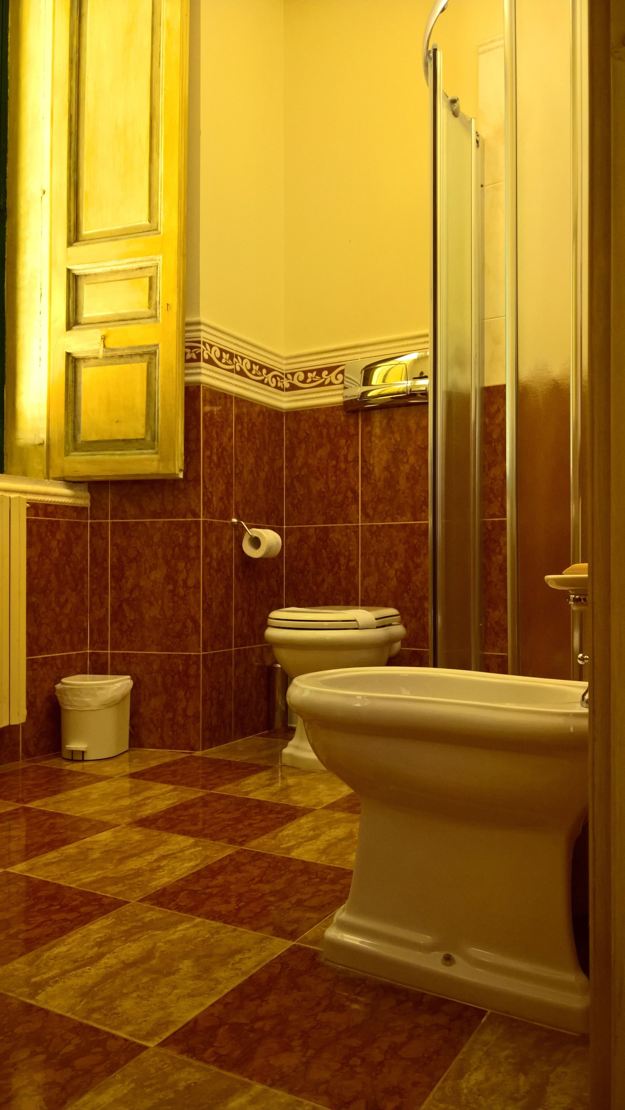 Un baño con inodoro, bidé y un cubo de basura.