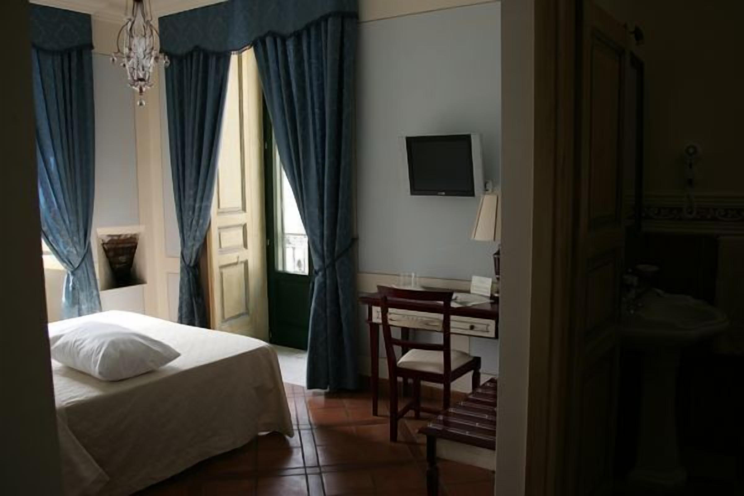 Une chambre d’hôtel comprenant un lit, un bureau, une chaise, une télévision et une salle de bain.