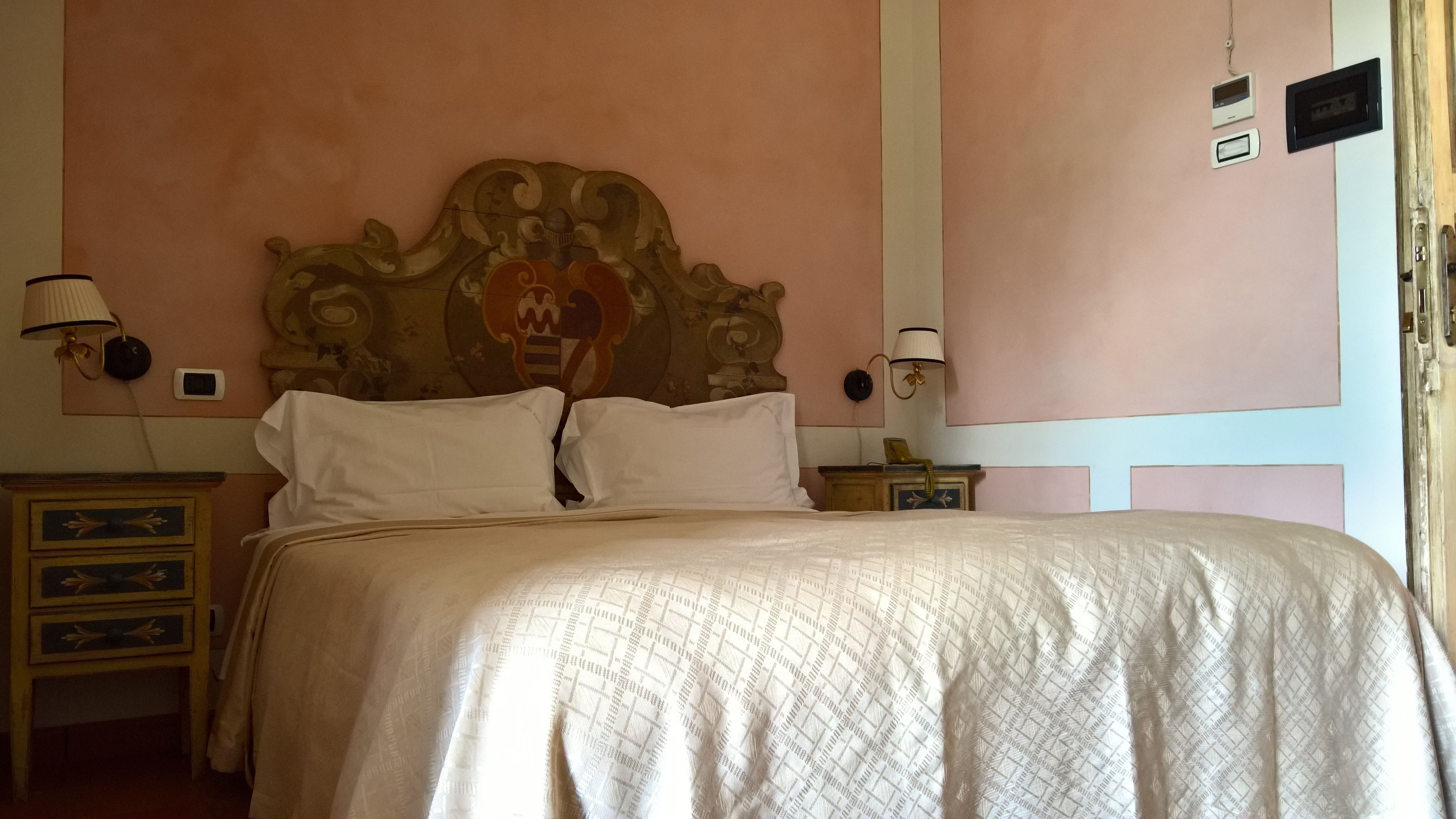 A bedroom with a large bed, two bedside tables, and a decorative headboard.