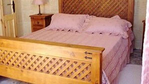 Une chambre à coucher avec un lit en bois, une table de chevet, une lampe et un mur décoré d’un motif.