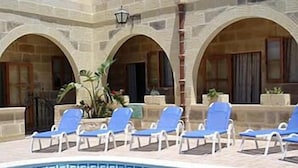 Un espace piscine agrémenté de chaises longues bleues et d’un bord de piscine orné de motifs.